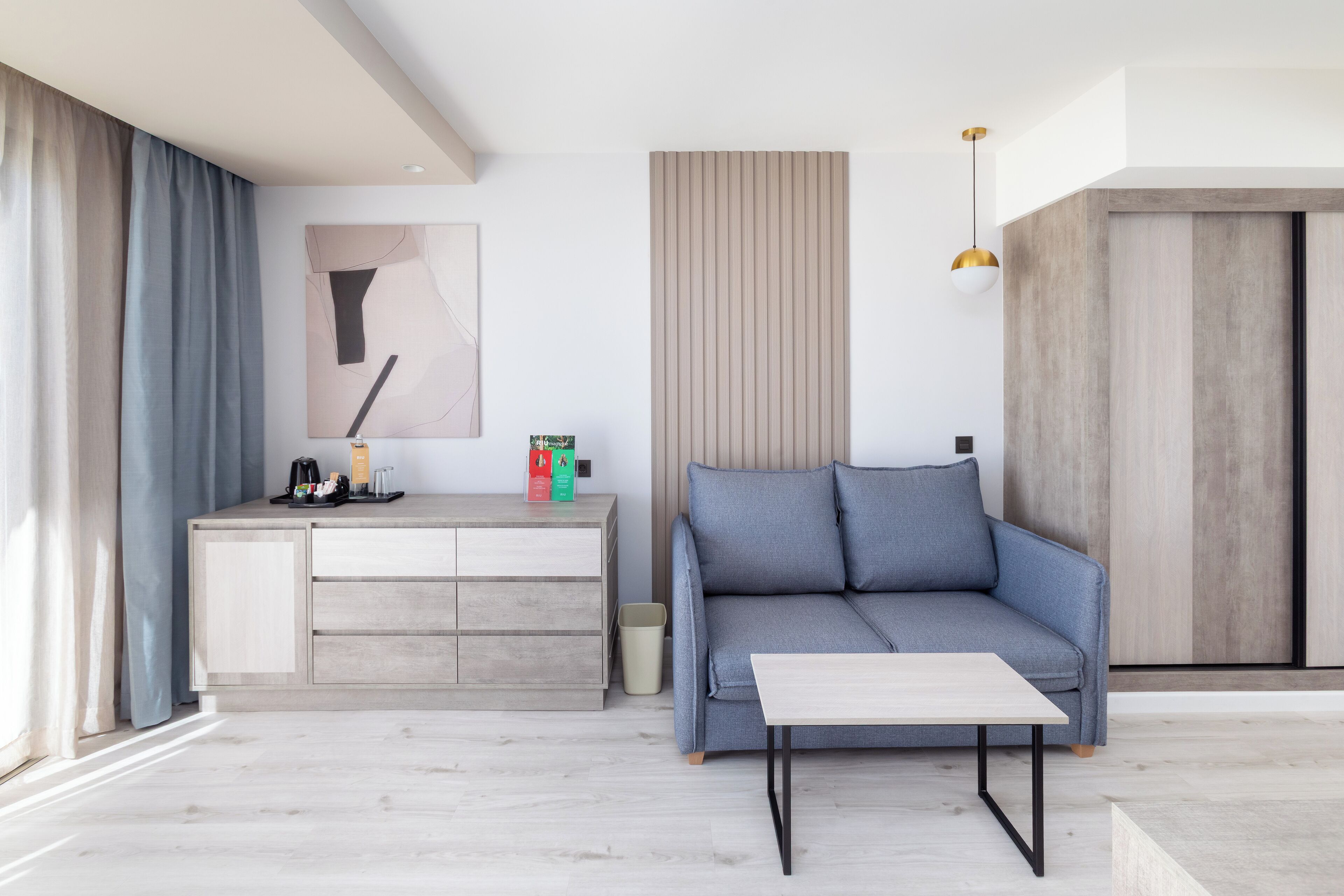 Ein modernes Wohnzimmer mit grauem Sofa, einem Holztisch und einem minimalistischen Design.