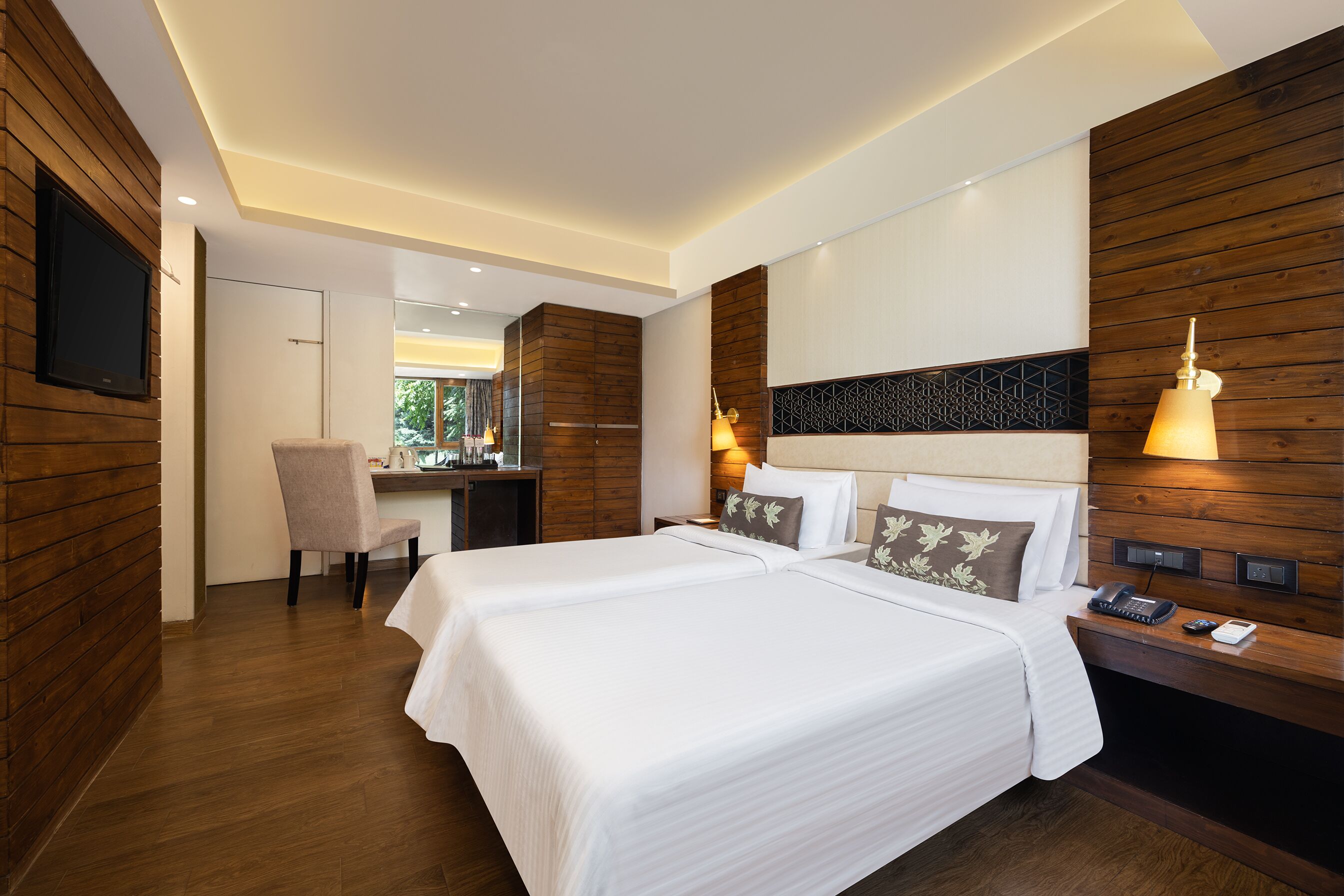 A hotel room with two beds, a desk, and a chair.
