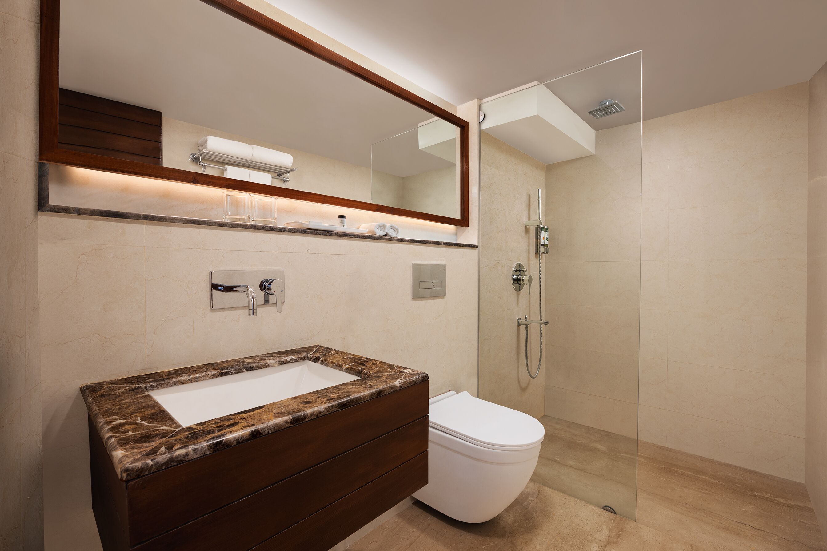 A modern bathroom with a marble sink, a white toilet, and a glass-enclosed shower.