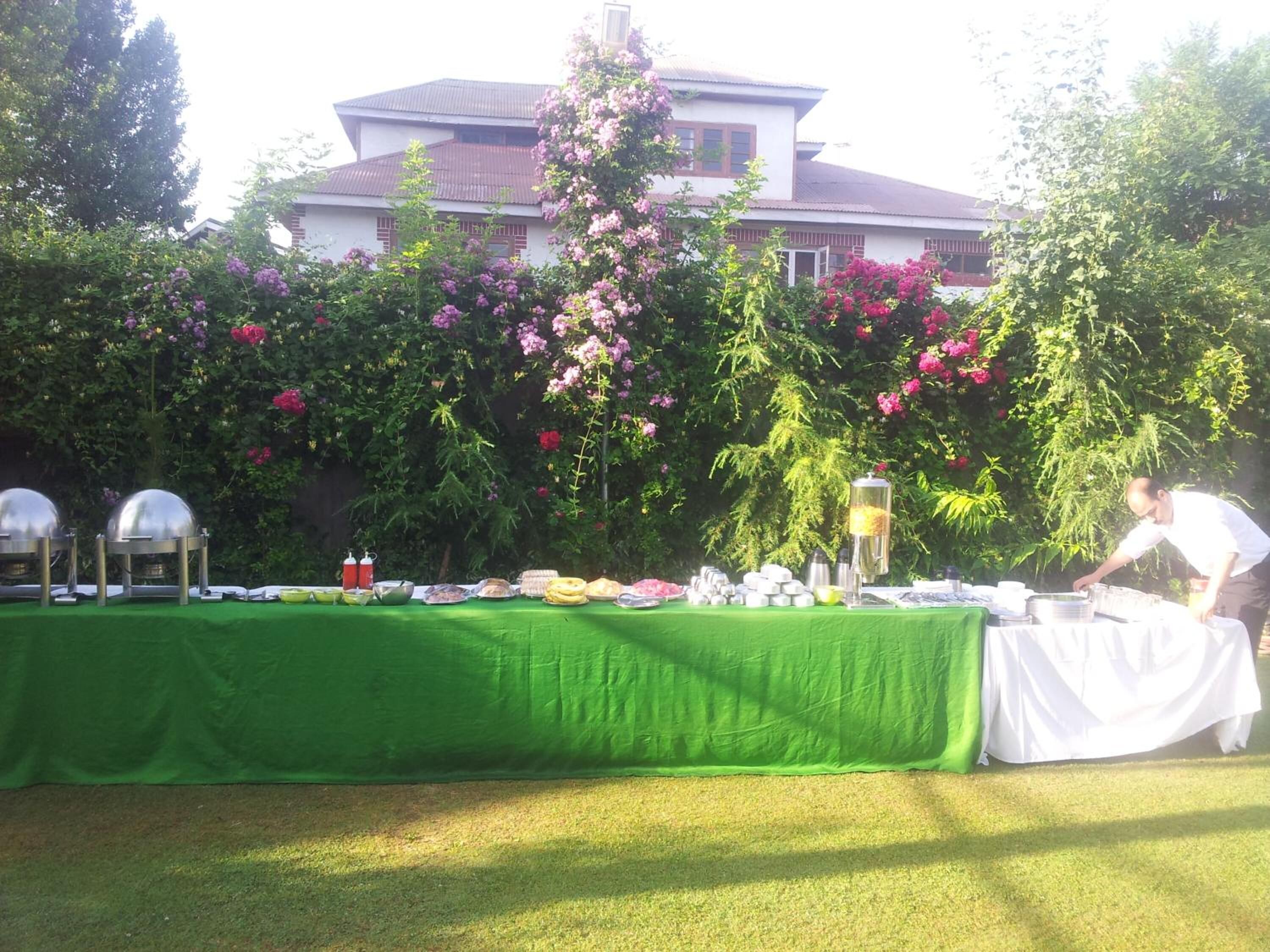 An outdoor buffet setup with a green tablecloth, food items, and a person serving.