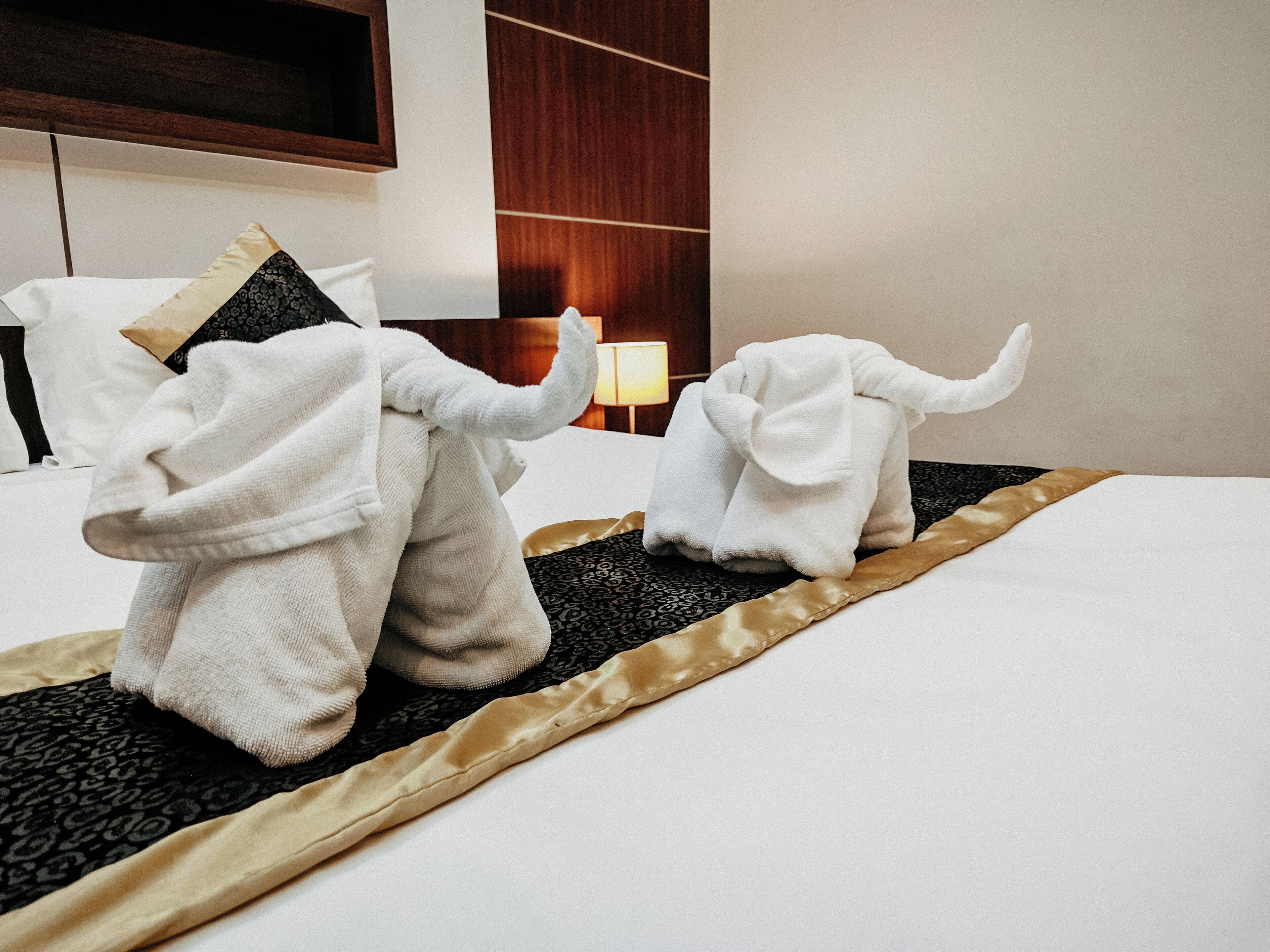 A hotel room with a bed, a lamp, and a wooden headboard.