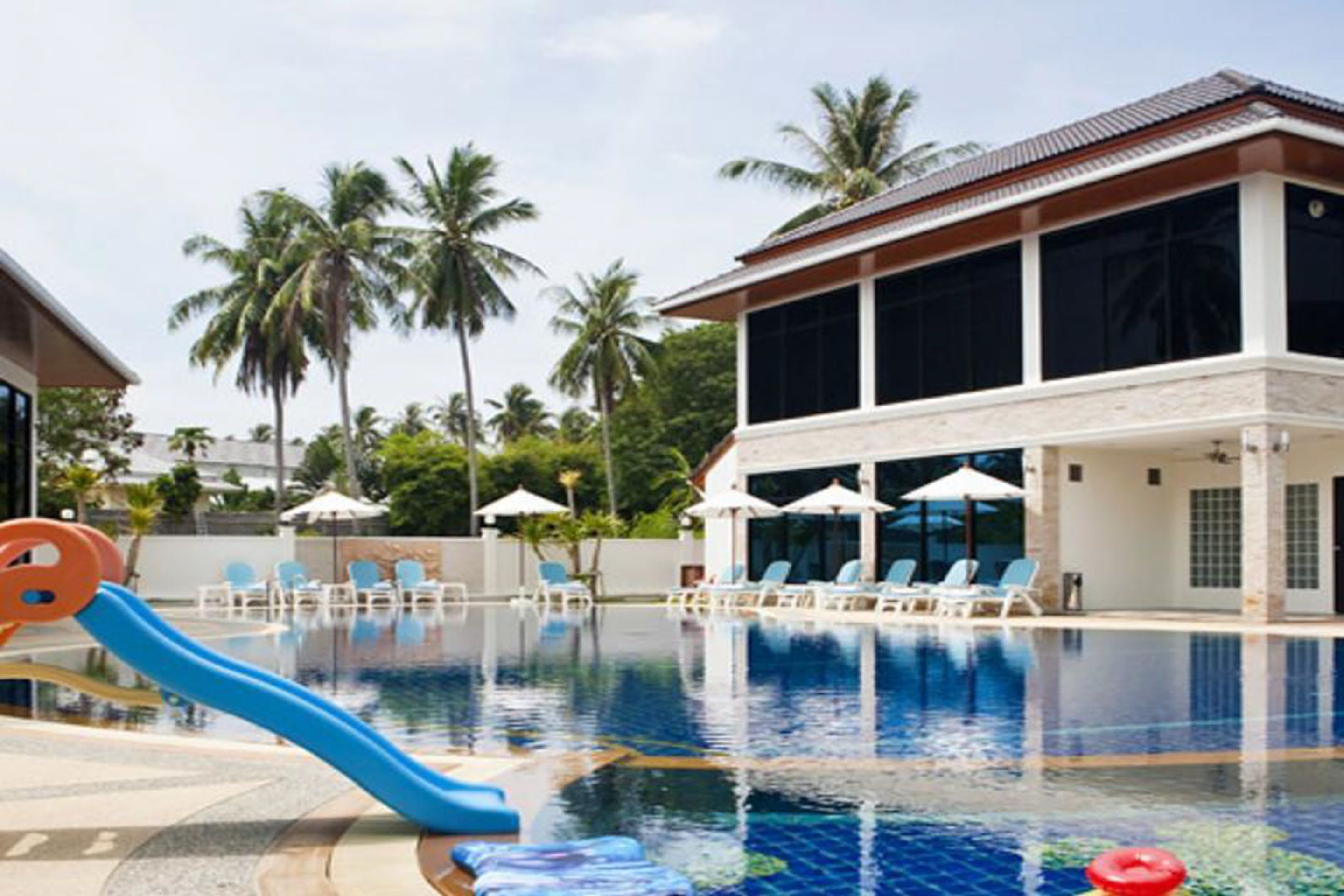 Piscina com escorrega azul, espreguiçadeiras e guarda-sóis.