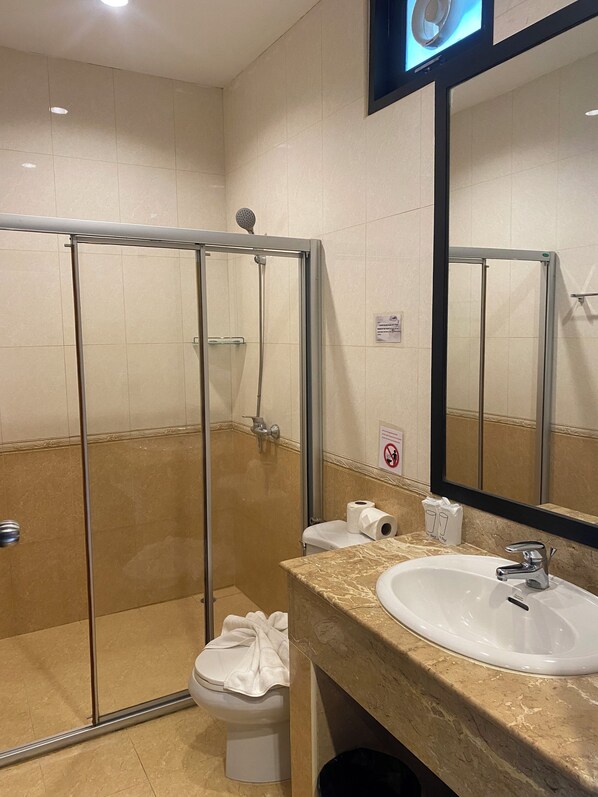 Une salle de bain avec une douche à parois de verre, un lavabo blanc et des toilettes.