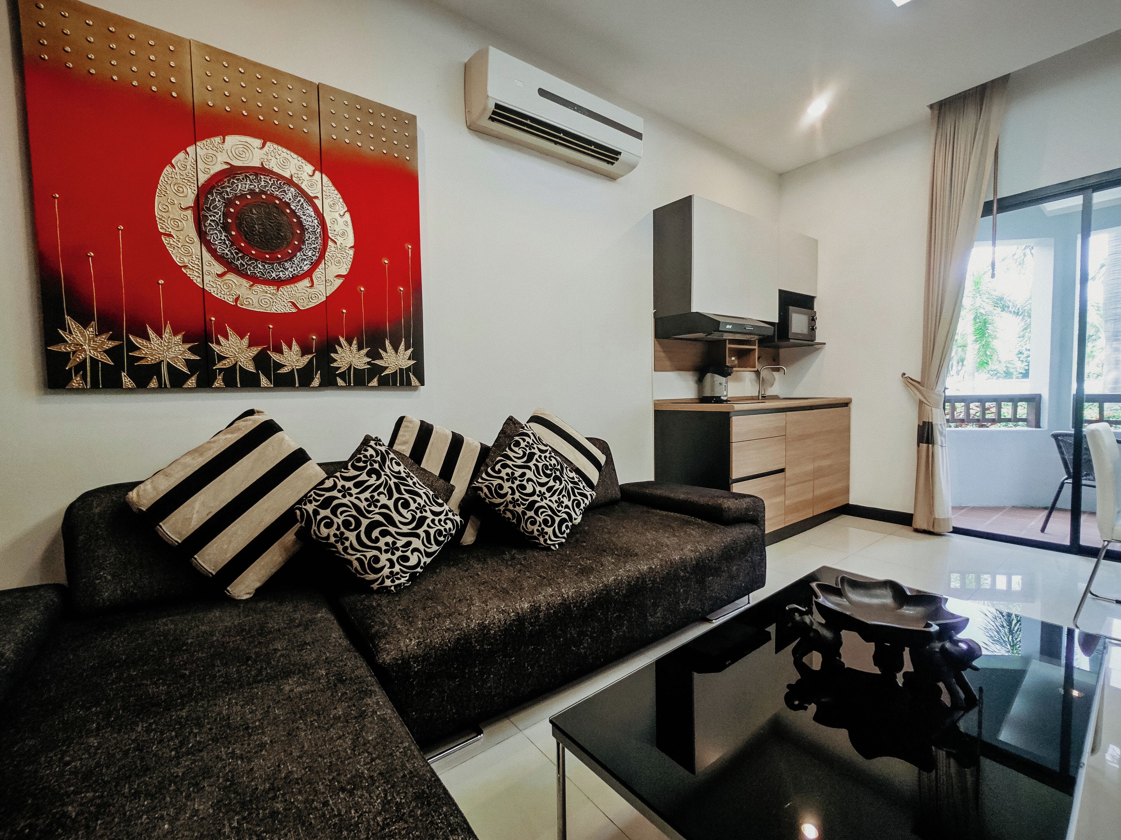 A modern living room with a sofa, patterned cushions, a coffee table, and a large wall art piece.