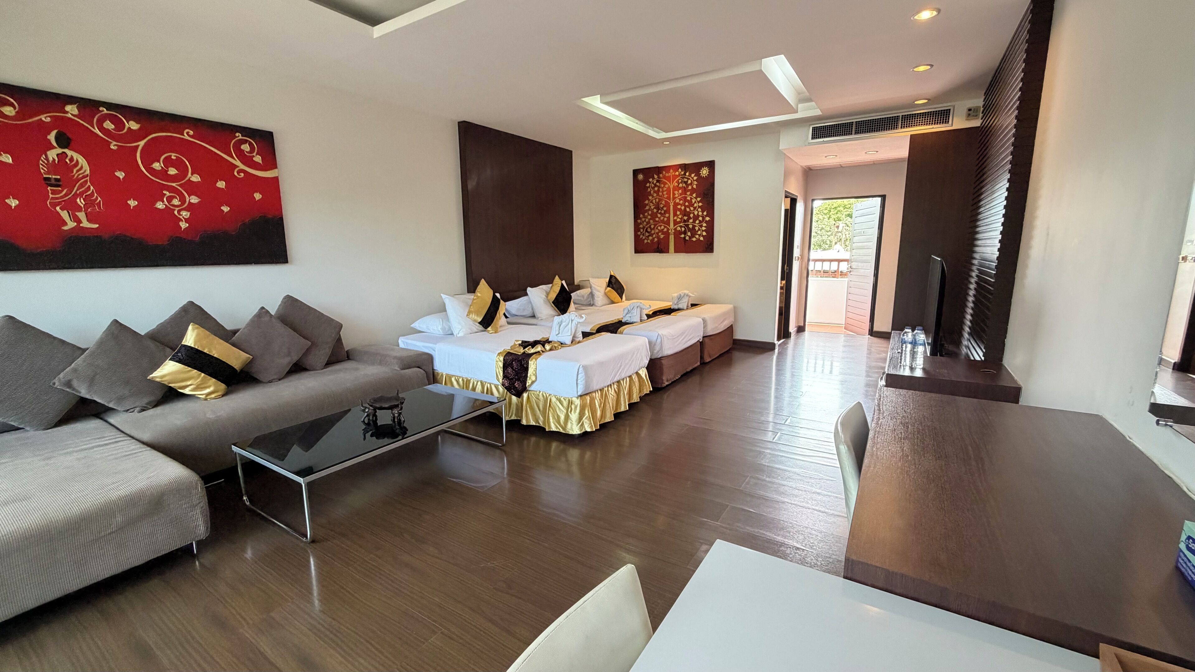 Una sala de estar moderna con sofá, una mesa de centro, una mesa de comedor y una cama con detalles dorados.