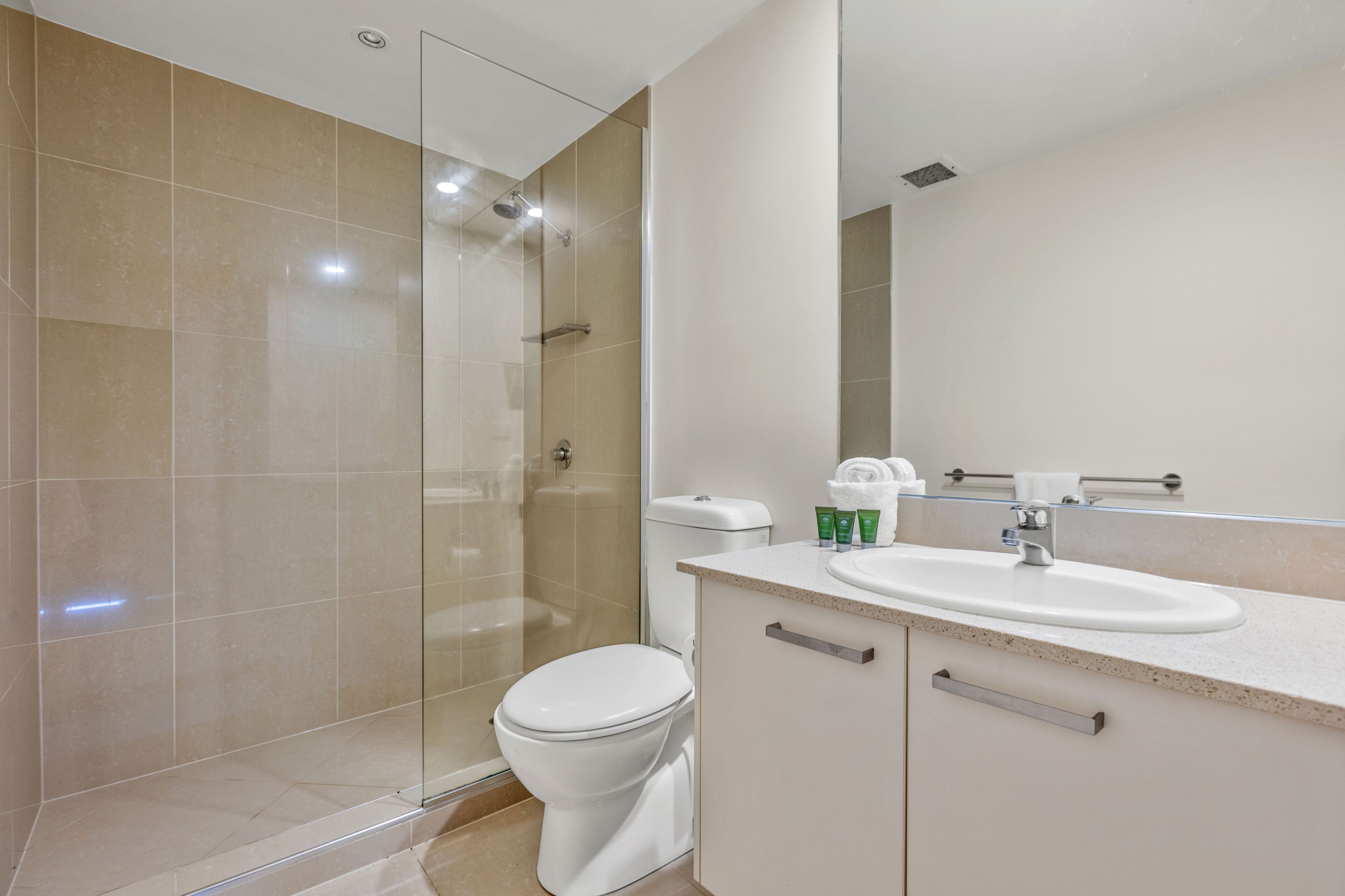Een moderne badkamer met een douchecabine van glas, een wit toilet en een wastafel met aanrechtblad.