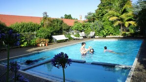 A swimming pool with lounge chairs and greenery around. - Airport Gold Star Motel (Auckland)