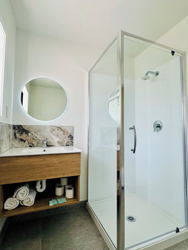 Deluxe studio suite | Badkamer | Een douche, een haardroger, handdoeken, zeep