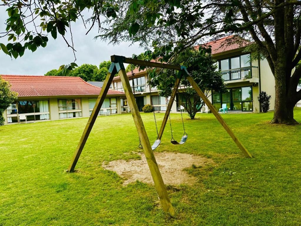 Baloiço numa área gramada, com um edifício ao fundo.