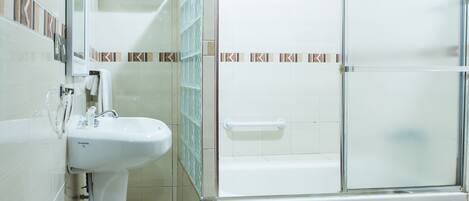 A bathroom with a white sink, a glass shower enclosure, and a tiled floor.