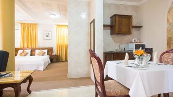 Una habitación de hotel con cama, una mesa de comedor para dos personas y una kitchenette.
