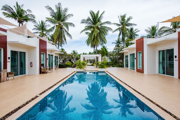 Una piscina con palmeras y edificios modernos al fondo.