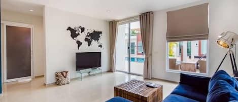 Un salon moderne avec un grand canapé bleu, une table basse en bois, un téléviseur à écran plat et une carte du monde accrochée au mur.