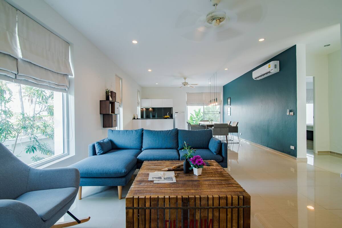Un salon moderne avec un canapé d’angle, une table basse en bois et un coin repas comprenant une table et des chaises.