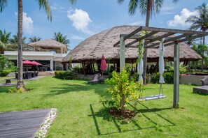 Un resort con una estructura de techo de paja, una terraza de madera y un césped bien cuidado.