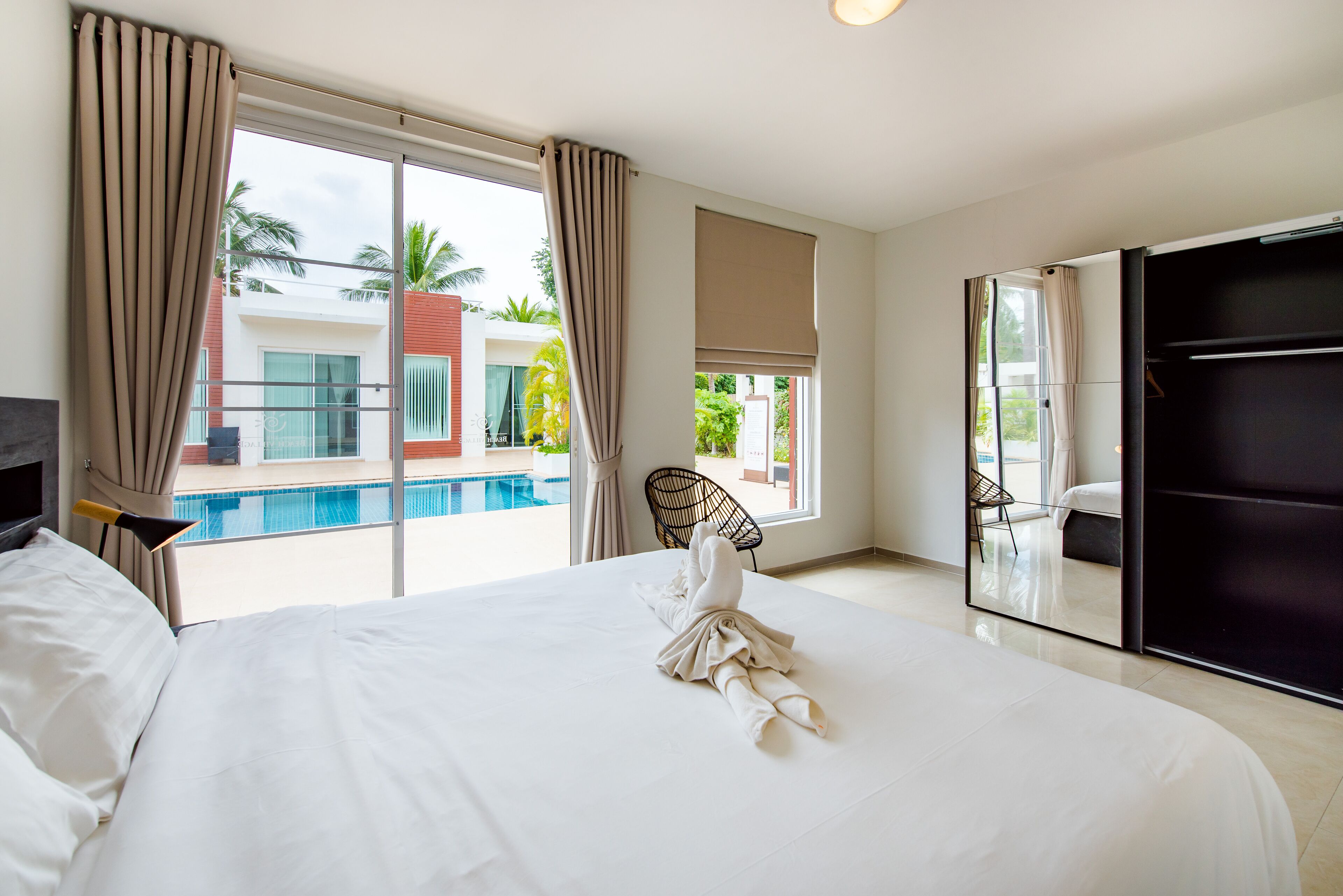 Habitación de hotel con una cama grande, vista a una piscina y puerta corrediza que da a un balcón.