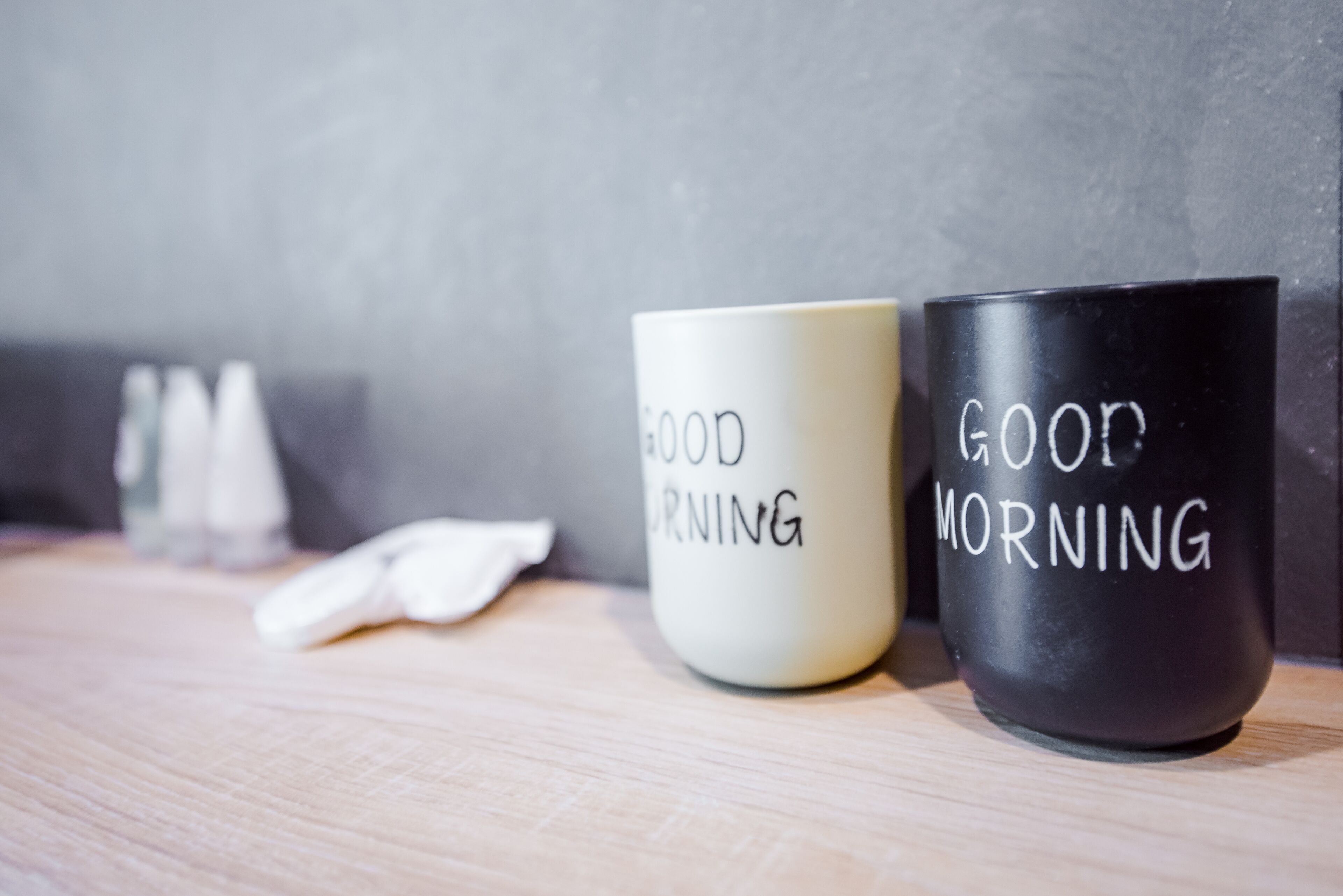 Two mugs with the text "GOOD MORNING" on a wooden surface.