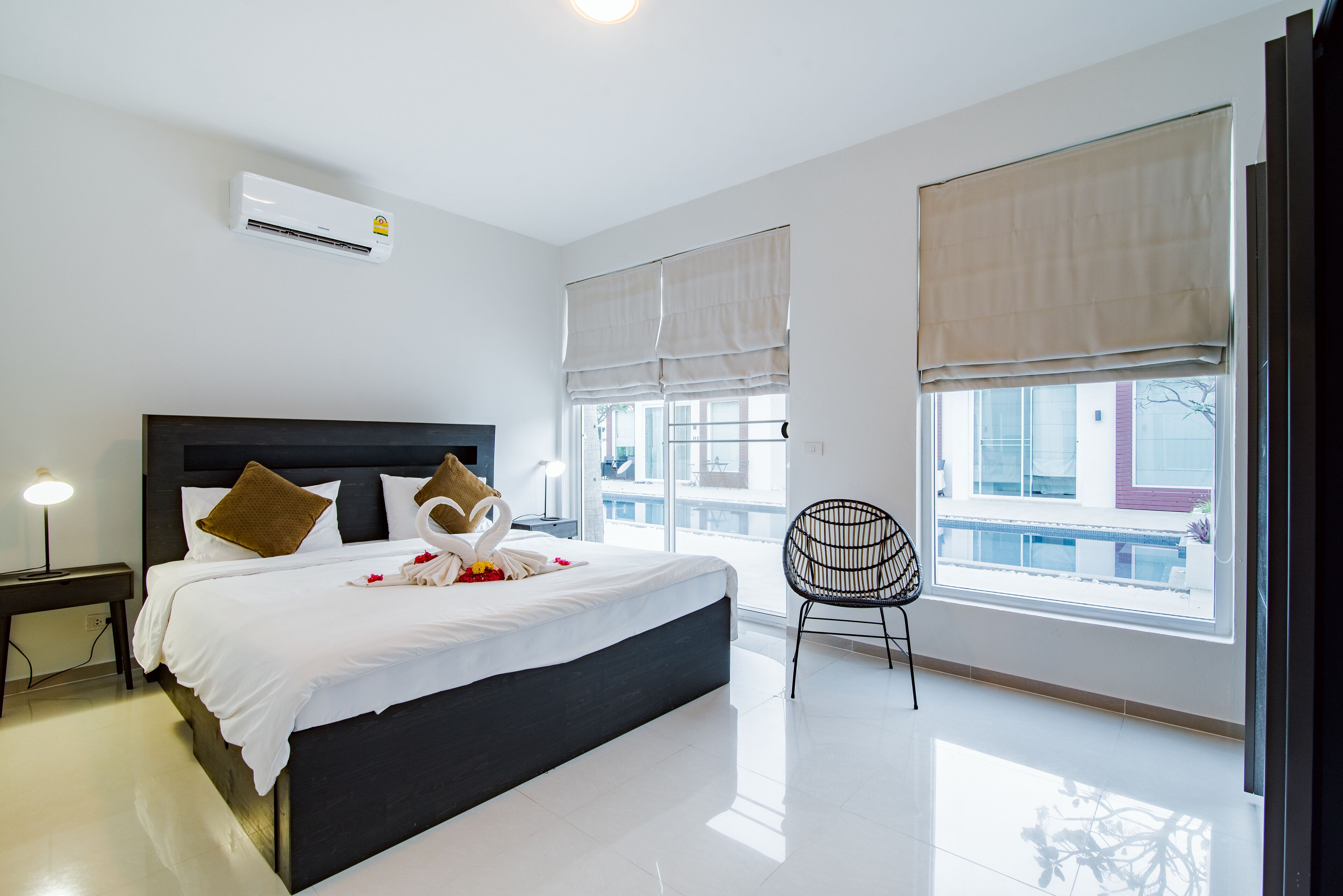 Habitación de hotel moderna con una cama grande, una silla y vistas de la ciudad a través de amplios ventanales.