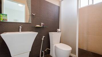 Un baño con lavamanos blanco, inodoro y zona de ducha.