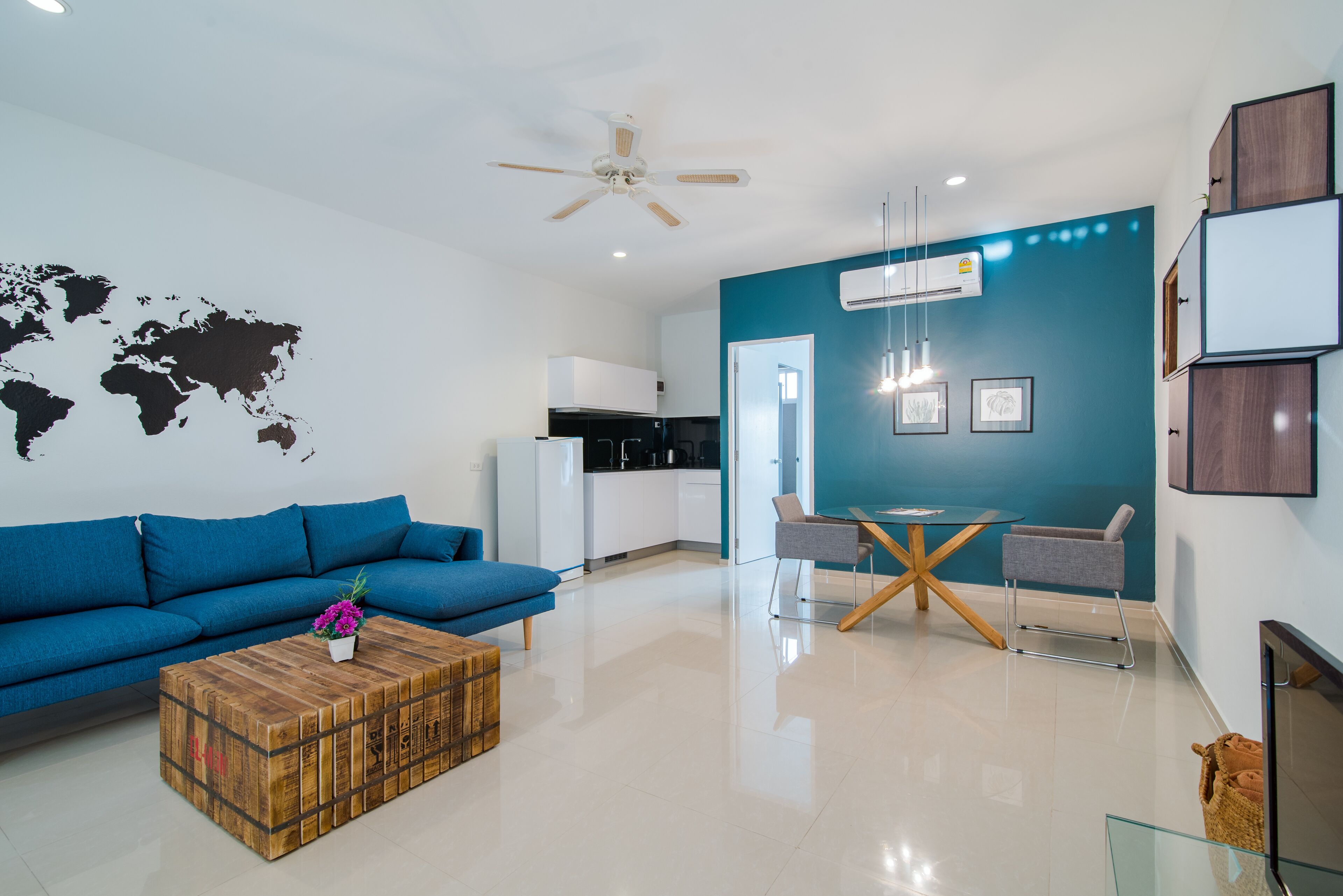 A modern living room with a blue sofa, a wooden coffee table, and a dining area with a table and chairs.