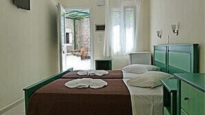 Una habitación con dos camas, un aparador verde y una ventana con cortinas.