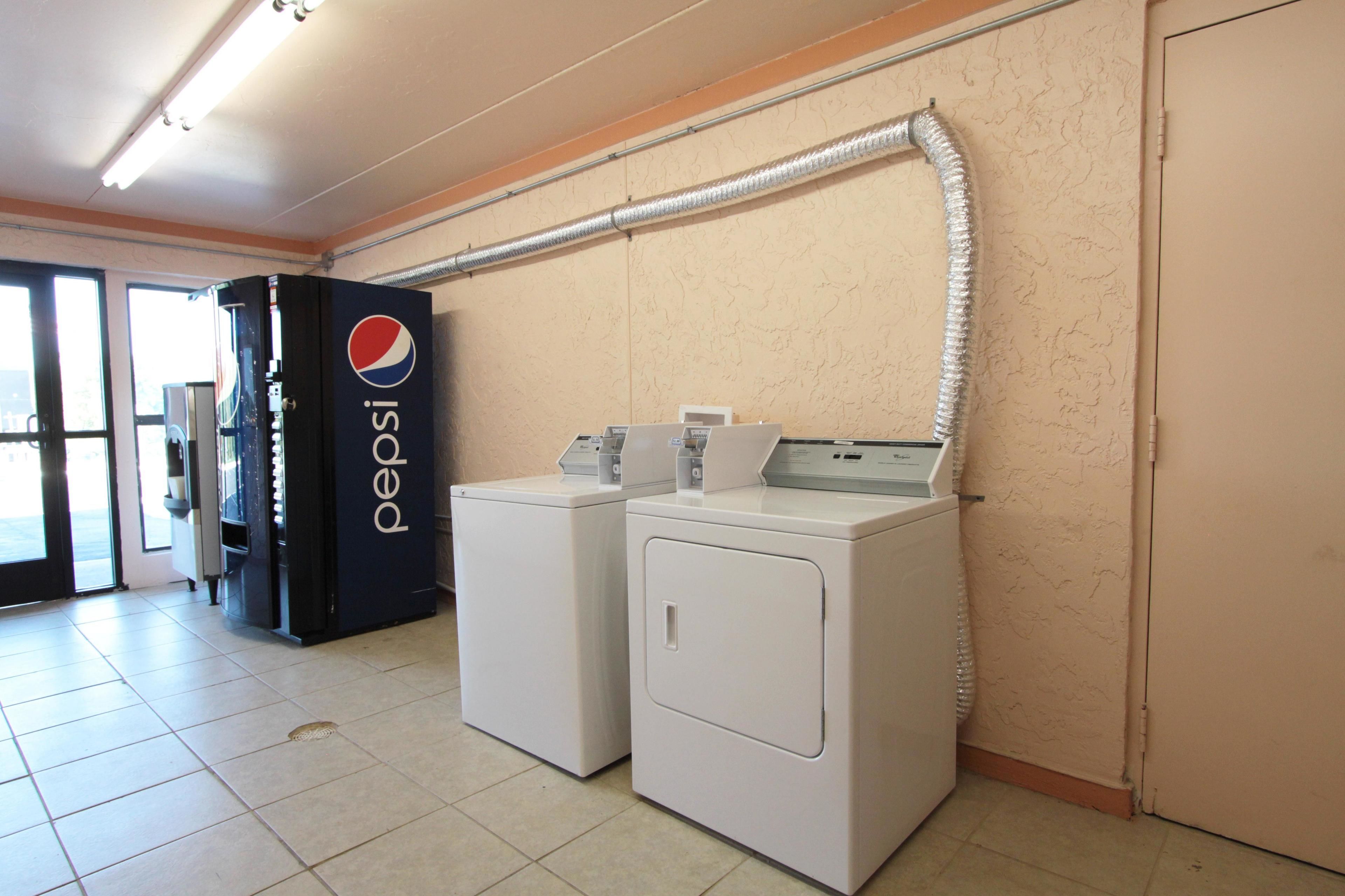 A laundry area with two washing machines and a Pepsi refrigerator.