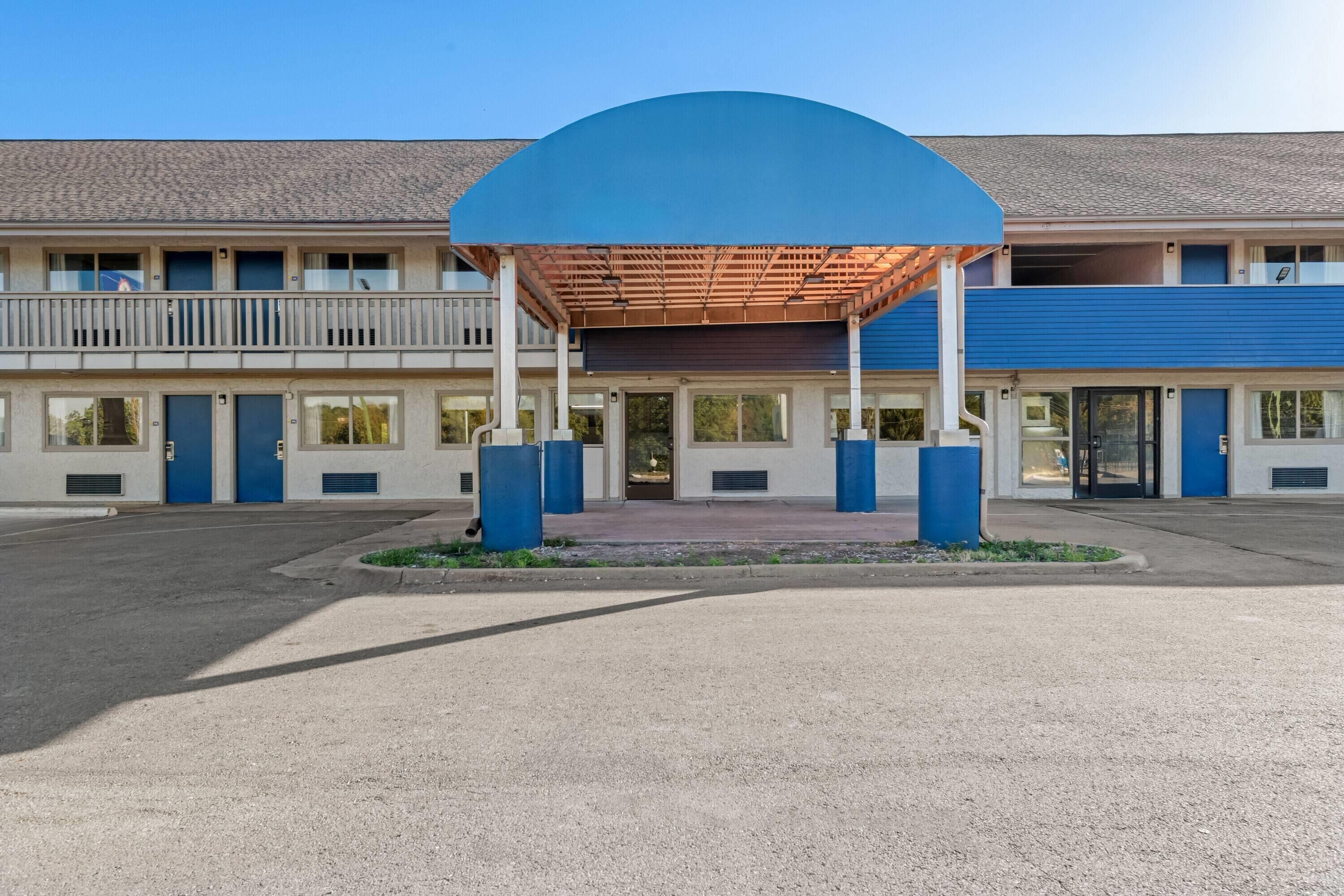 A building with a covered entrance, multiple doors, and a balcony.