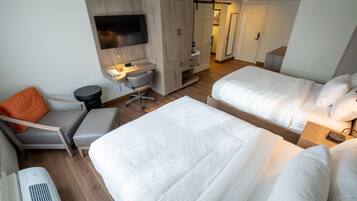 A hotel room with two beds, a desk, a chair, a TV, and a wardrobe.