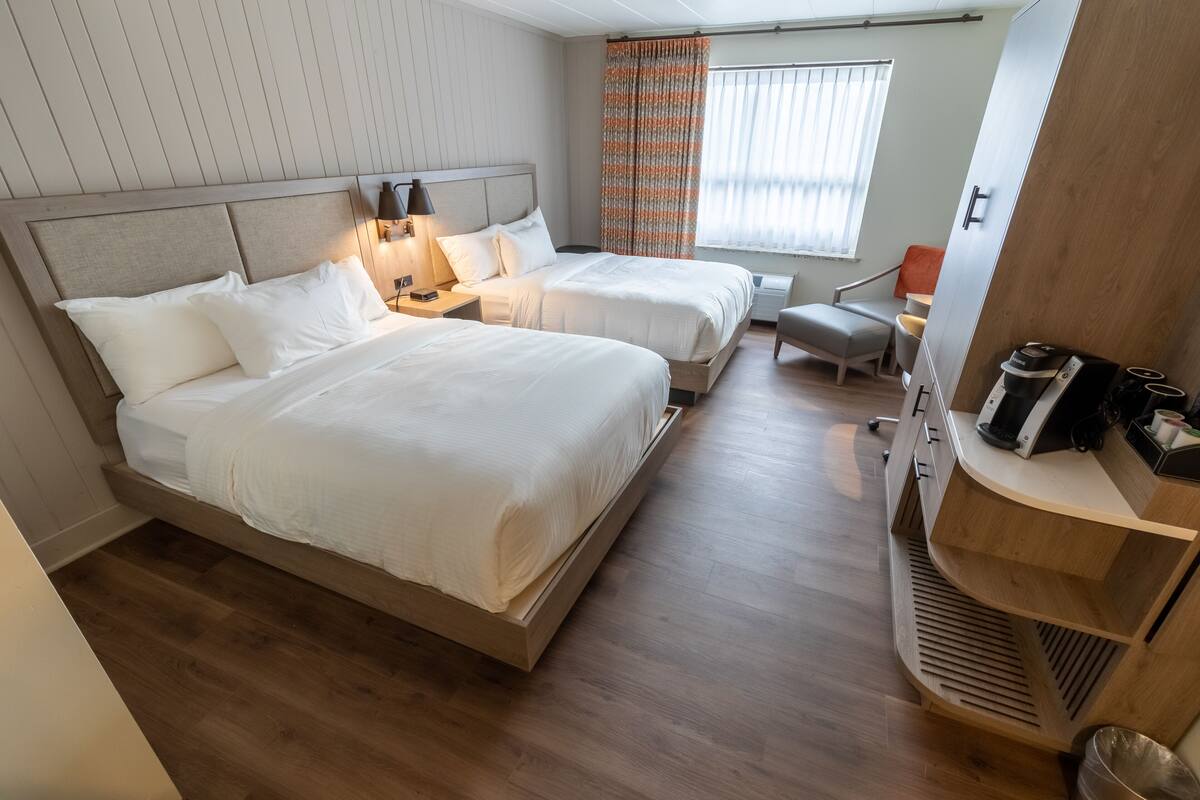Une chambre d’hôtel avec deux lits, un bureau, une chaise et une kitchenette.