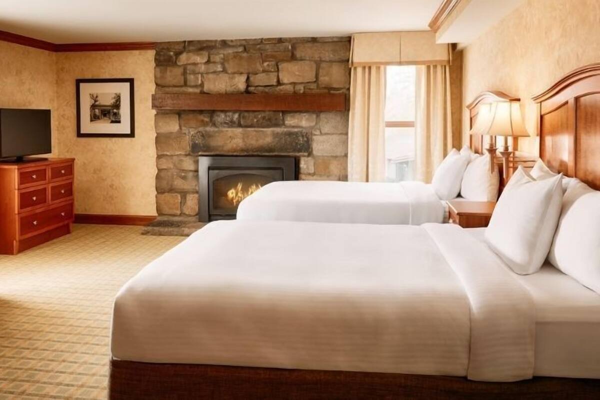 Une chambre d’hôtel avec deux lits, une cheminée, une télévision et un bureau.