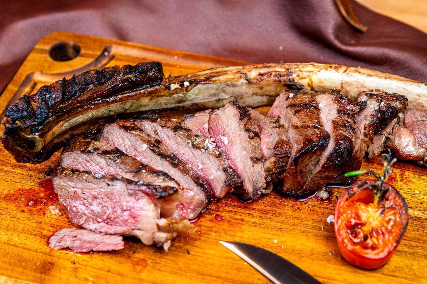 Een steak met een aangebrande korst op een houten snijplank.