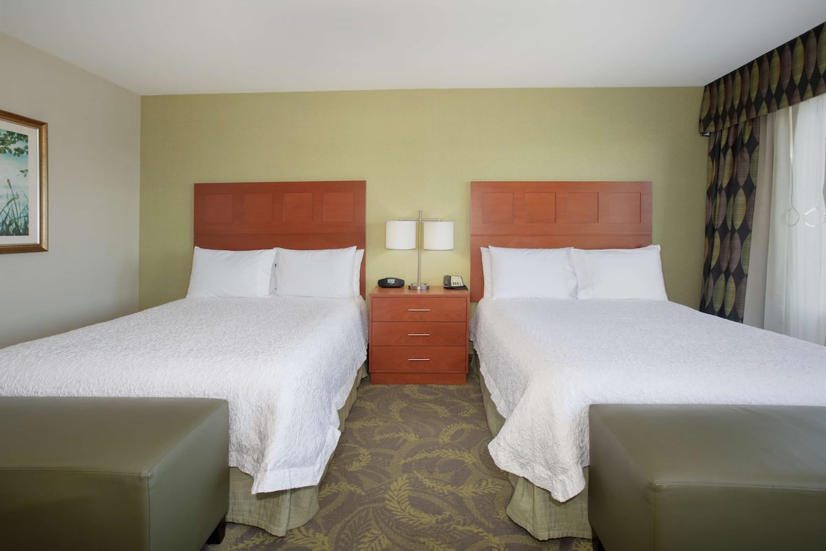 Une chambre d’hôtel avec deux lits, une table de chevet et une petite table.