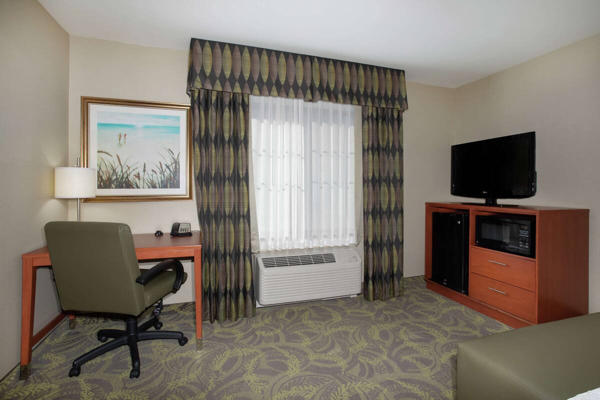 Une chambre d’hôtel équipée d’un bureau, d’une chaise, d’une télévision et d’un lit.