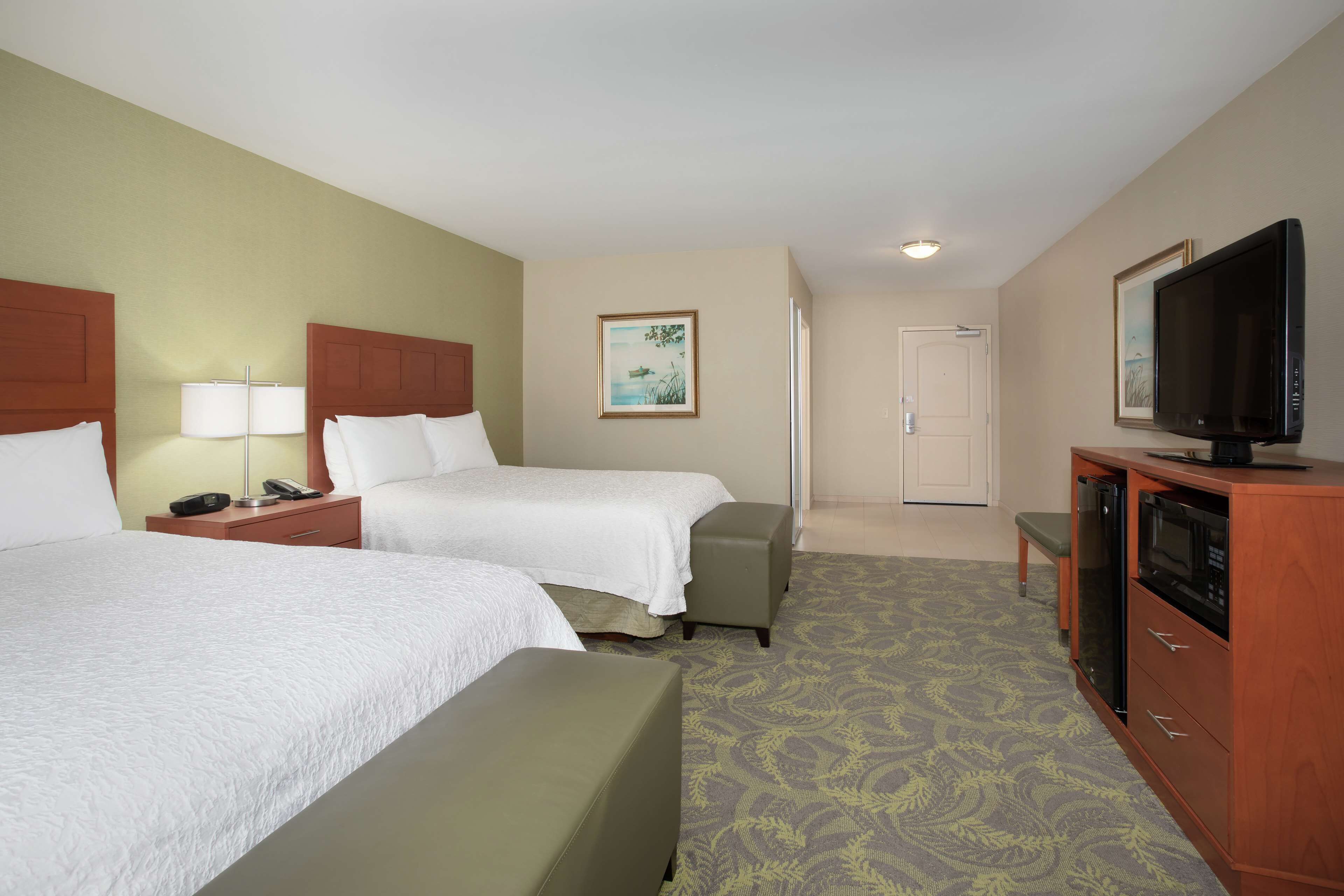 A hotel room with two beds, a television, a desk, and a cabinet.