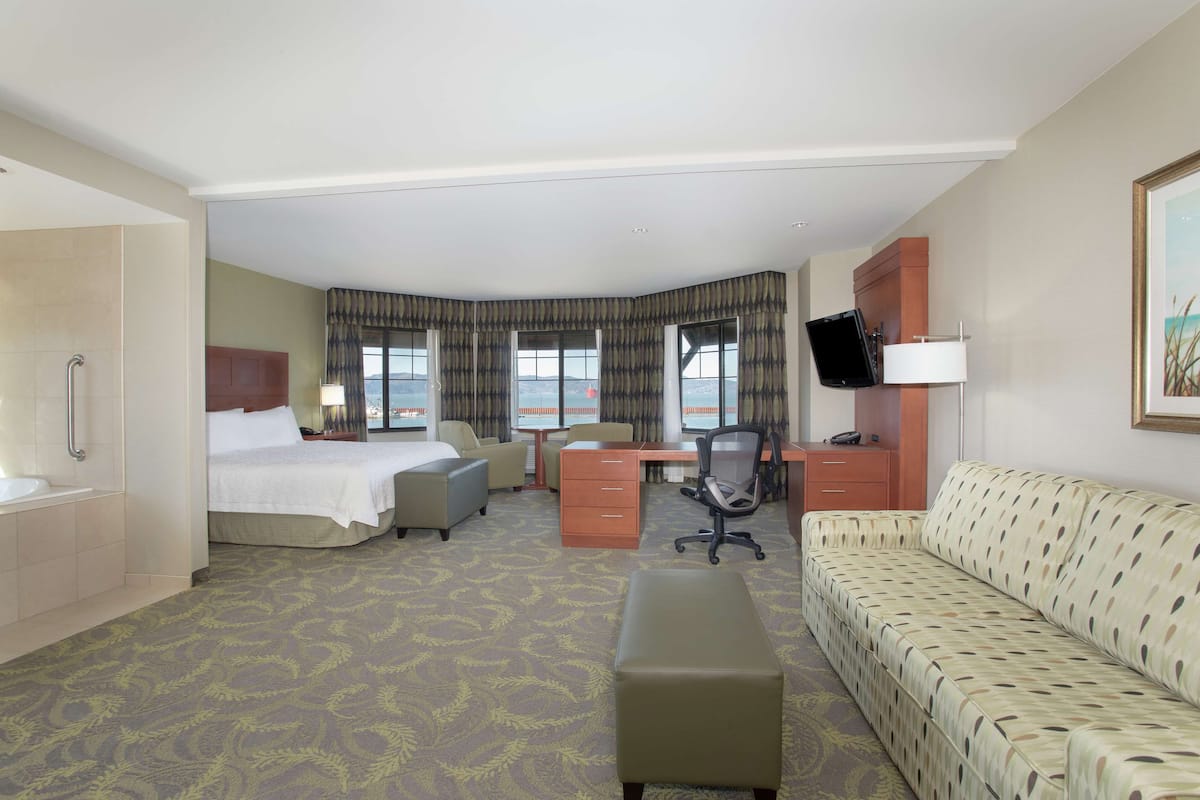 Une chambre d’hôtel équipée d’un lit, d’un bureau, d’un fauteuil de bureau, d’un canapé et d’une télévision.