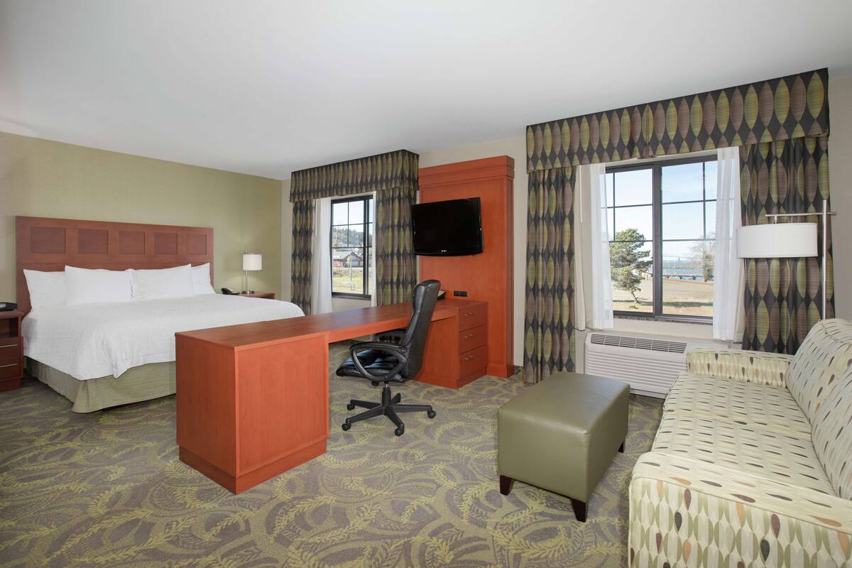 Une chambre d’hôtel avec un lit, un bureau, une chaise et un canapé.