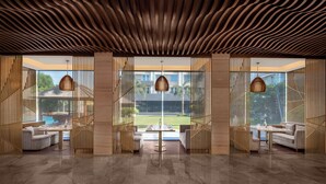 A modern interior with a wavy ceiling, large windows, and a central seating area with a table and chairs.