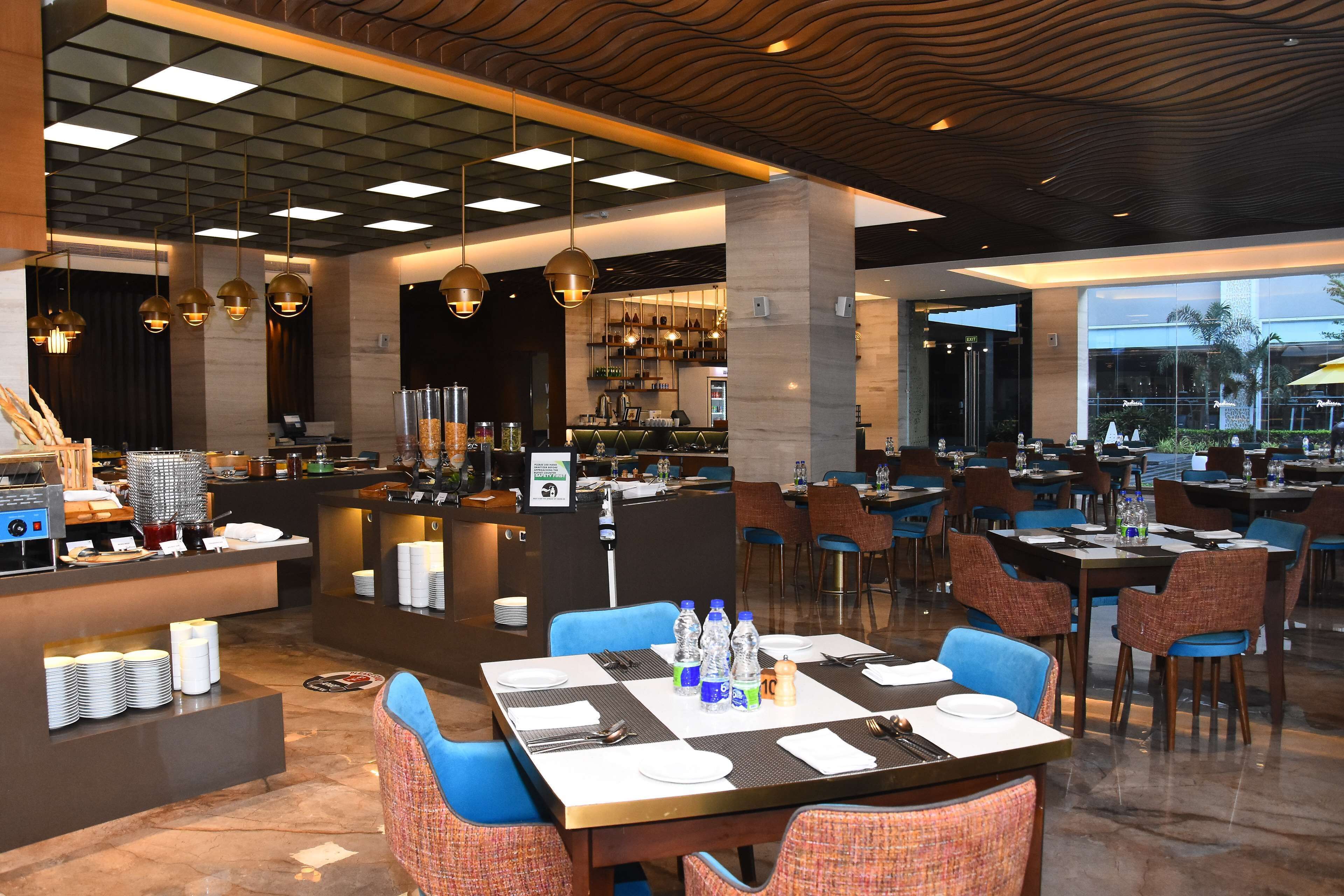 A modern restaurant with a bar area, multiple dining tables, and blue chairs.