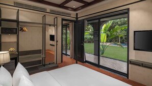 A hotel room with a large bed, a TV, a wardrobe, and a sliding glass door to the outdoors.