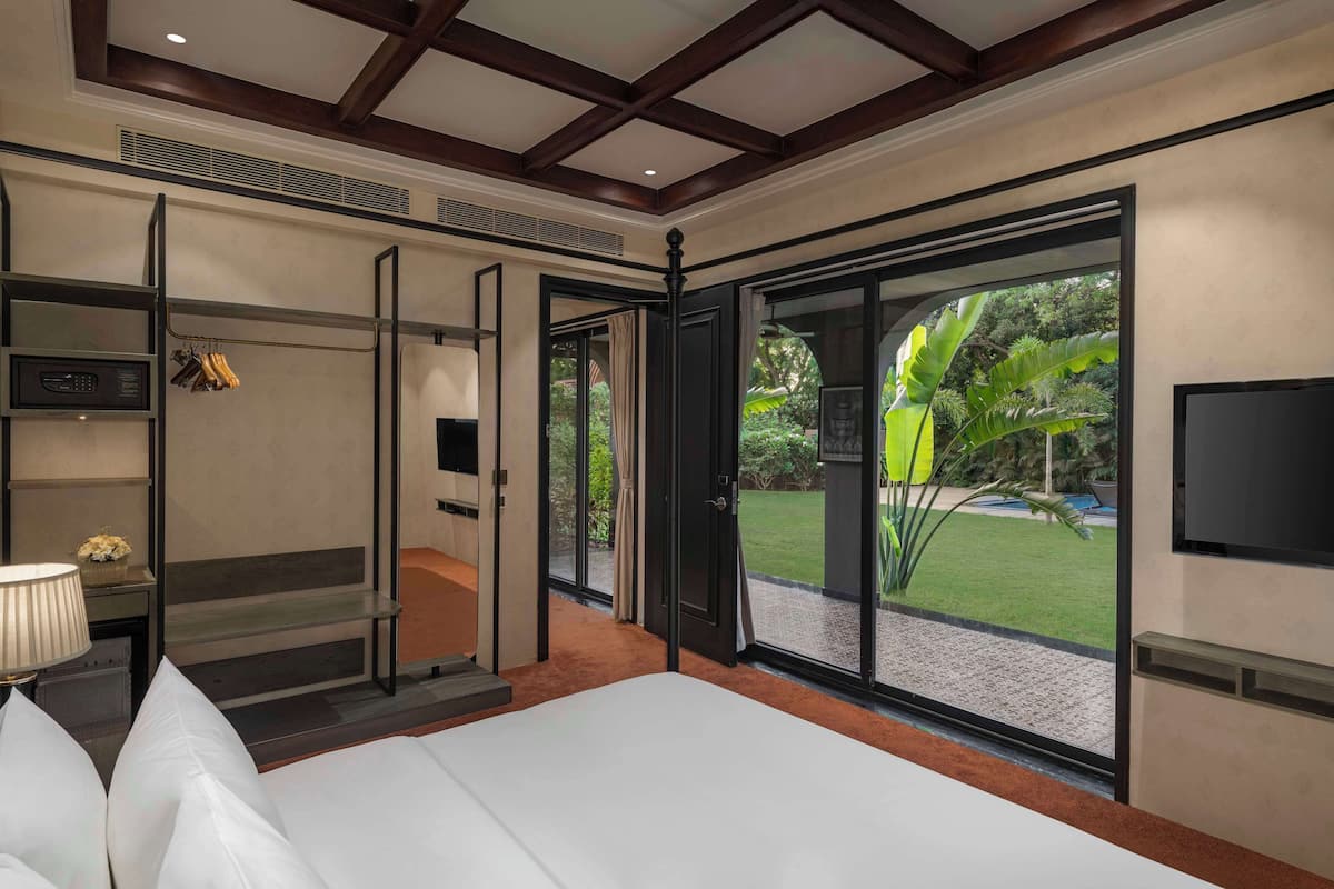 Habitación de hotel con una cama grande, televisión, armario y puerta corrediza de cristal al exterior.