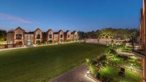 A hotel with multiple wing-like structures, a well-maintained lawn, and a landscaped garden area.
