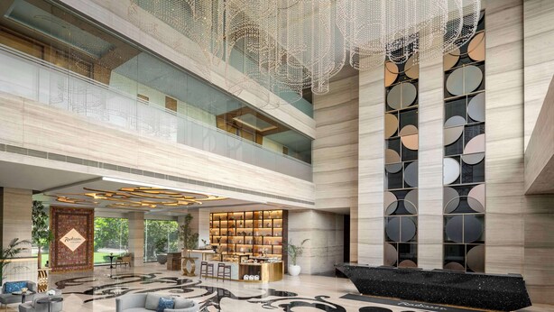 A spacious lobby with a reception desk, seating area, and a decorative wall with circular patterns.