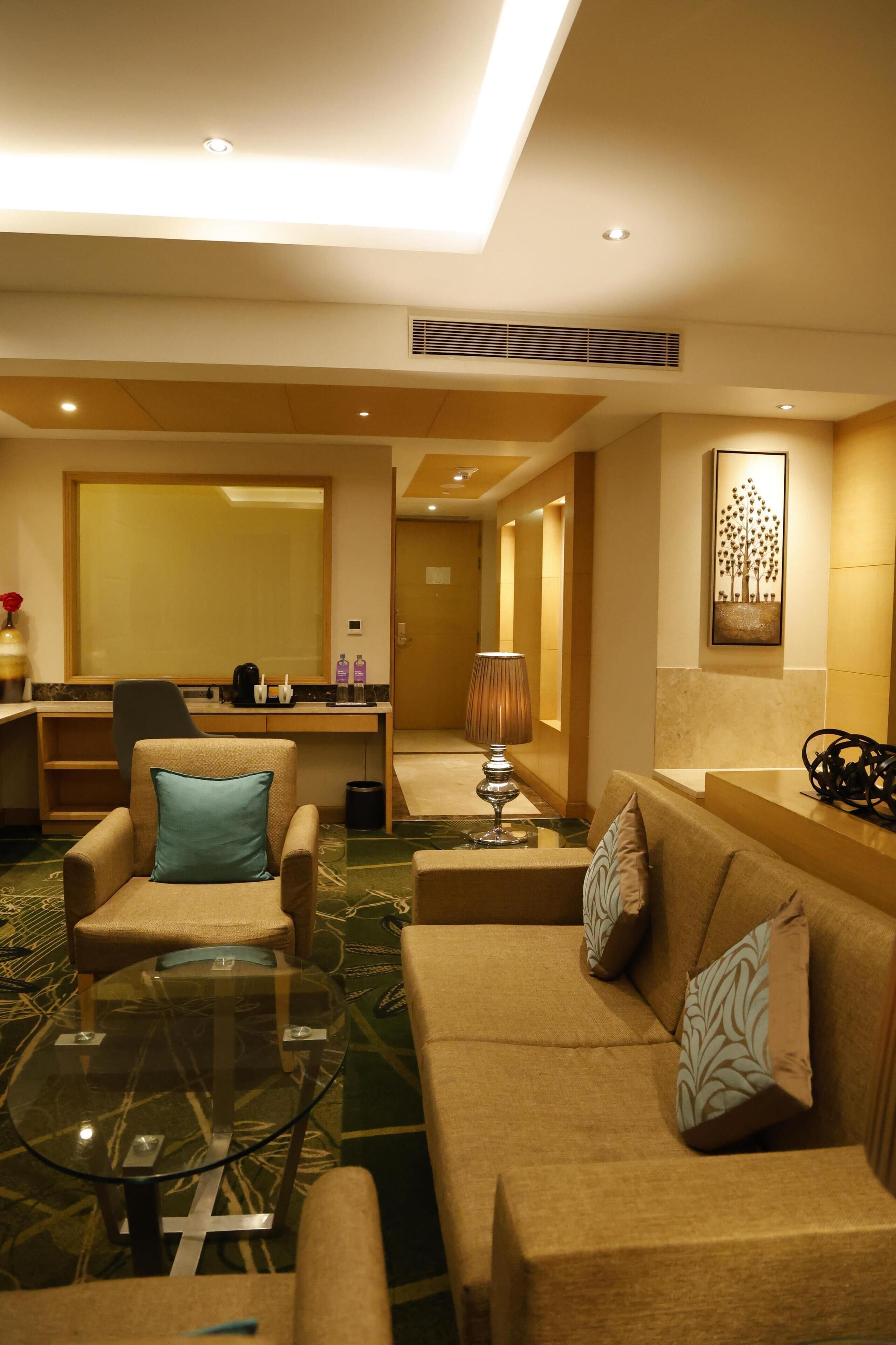 A hotel lobby with a seating area, a reception desk, and a large mirror.