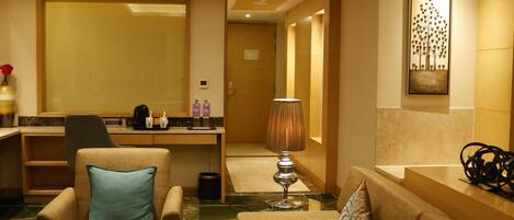 A hotel lobby with a seating area, a reception desk, and a large mirror.