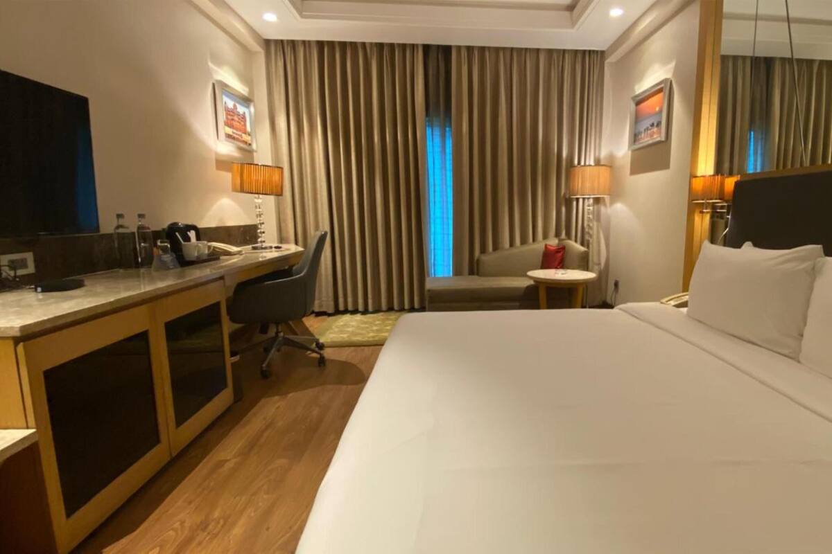 Una habitación de hotel con una cama grande, un escritorio con silla, una mesita redonda pequeña y un sofá.