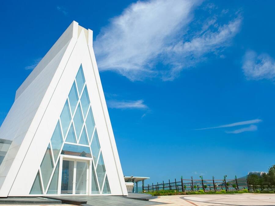 A modern white building with a triangular facade and large windows.