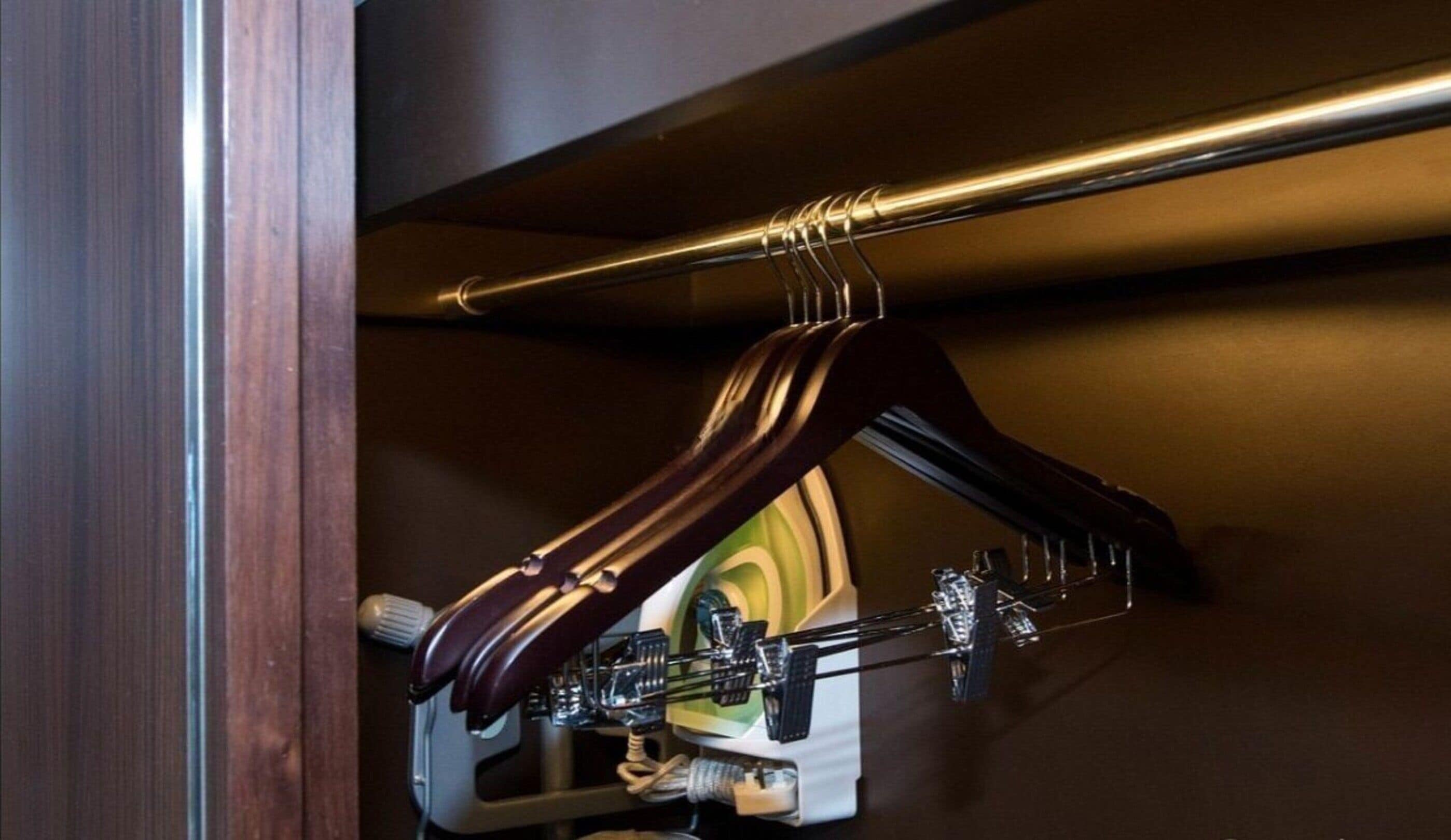 A wooden hanger with a metal rod and a white device attached to it.