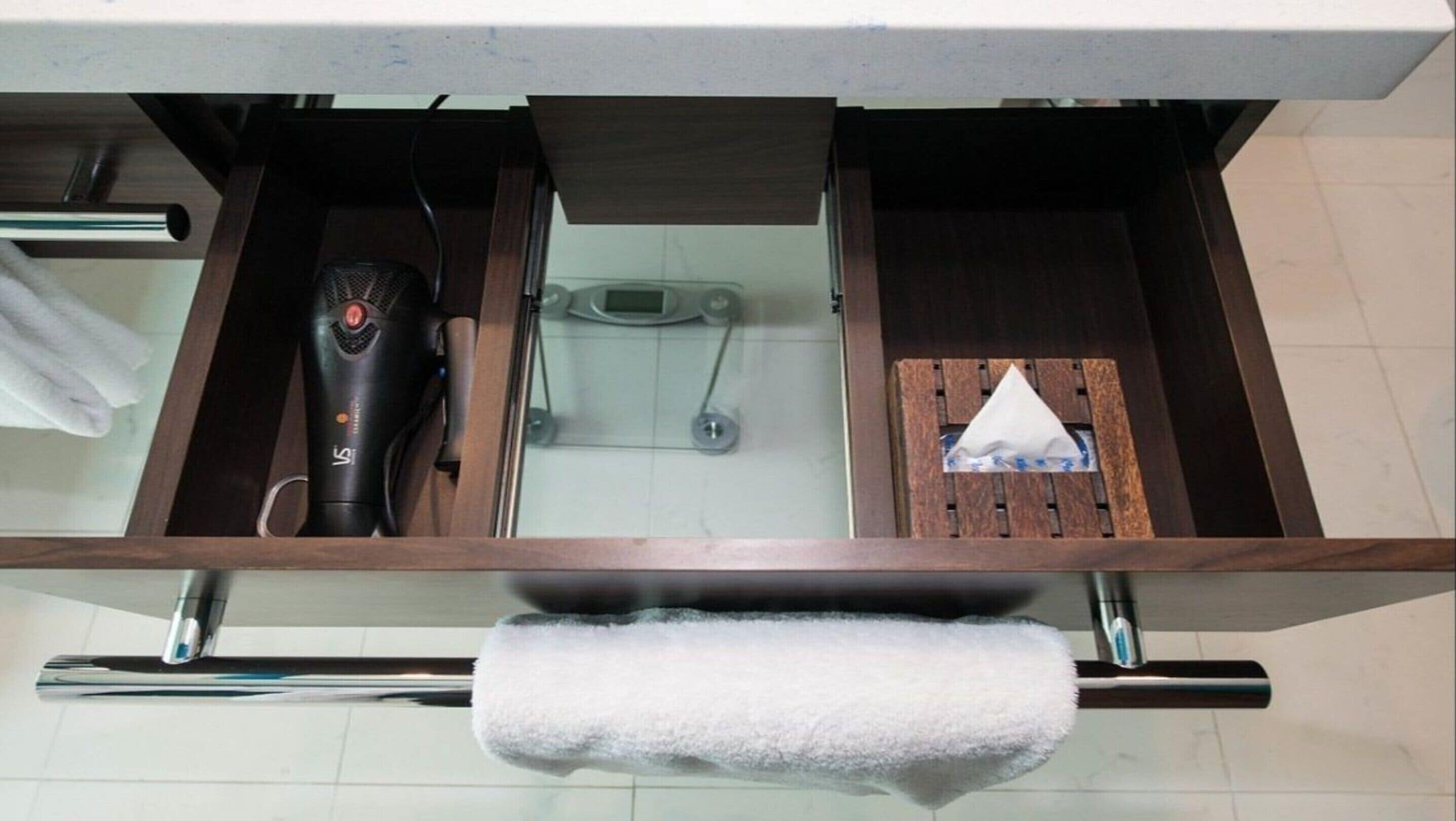 A bathroom with a wooden vanity, a hairdryer, a scale, and a tissue box.