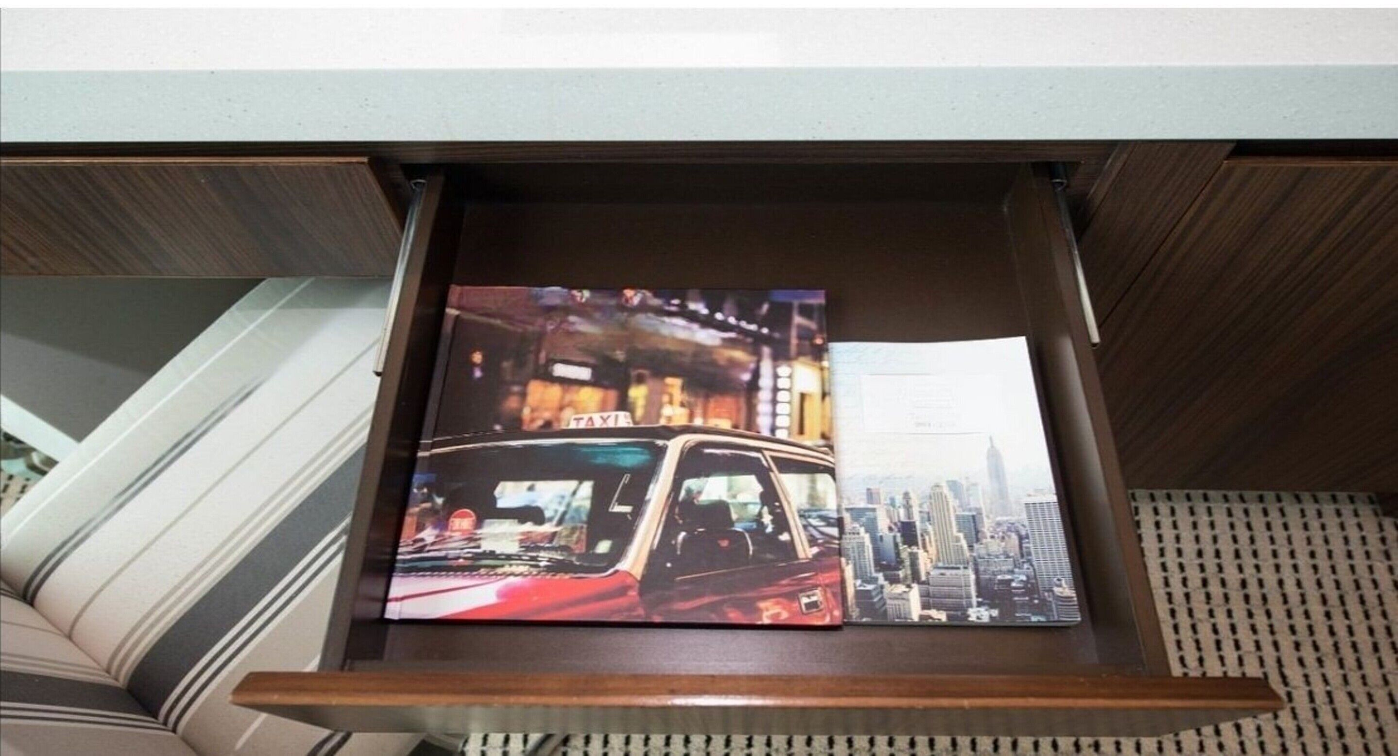 A cityscape view through a window, with a wooden frame and a patterned cushion visible.