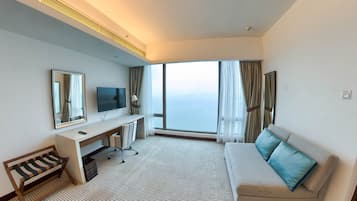 Een hotelkamer met een groot raam, een bureau met stoel, een bank en een televisie.
